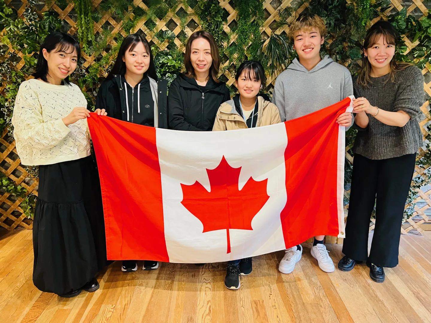 カナダ国旗を囲む留学生と現地サポートスタッフ
