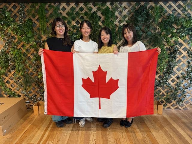 カナダ国旗を囲む留学生と西岡彩・現地スタッフ